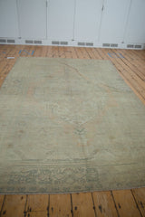 Intact selvage and faded sage green plant motif border of distressed Oushak rug.