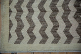 Distressed Tulu rug's textured cream and brown chevron, showing fringed end and side selvage.