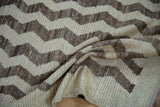 Textured pile detail of a vintage distressed Tulu rug with cream and brown chevron motif.