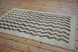 Distressed vintage Tulu rug corner with textured cream and brown chevron pattern, thin border.