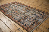Distressed vintage Hamadan rug corner showing worn Herati pattern, vine border, and foundation.