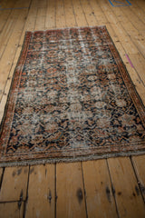 Close-up of vintage distressed Hamadan rug corner, showing faded Herati pattern and worn fringe.