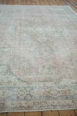 Distressed texture of the vintage Sparta carpet, with soft pink and blue floral motifs.