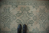 Distressed Oushak rug runner showing celadon green floral motifs, visible texture, and narrow border.