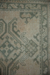 Distressed vintage Oushak rug pile, revealing dusty celadon green and beige floral details.