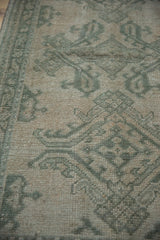 Distressed pile texture of an Oushak rug, with worn celadon green patterns on a beige ground.