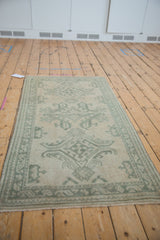 Vintage distressed Oushak runner with narrow celadon green border, worn floral field, and intact selvage.