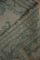 Distressed Oushak runner's worn pile, showcasing visible knot heads in dusty celadon green and beige.