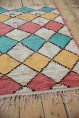Moroccan rug's harlequin diamond pattern with ivory, saffron yellow, dusty pink, and pale turquoise.
