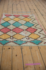 Vintage Moroccan rug showing patterned pile with pink, turquoise, saffron, and ivory diamonds.