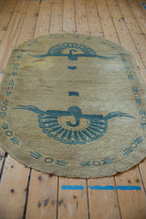 Vintage Art Deco rug's curved edge, beige field and dusty denim blue banded geometric border.