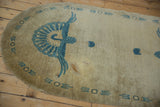 Blue peacock design with geometric border on beige Chinese Art Deco rug, displaying a spot stain.
