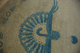 Stylized peacock design in dusty denim blue on the beige field of an Art Deco rug.