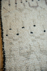 Thick, shaggy ivory pile with scattered black pattern dots and dark cord selvage.