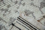 Shaggy ivory and gray pile of the vintage Moroccan rug, revealing a striped woven reverse.