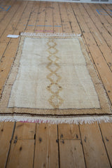 Hand-knotted pile texture, ivory fringe, and dark banded end of the vintage Moroccan rug.