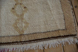 Vintage Moroccan rug: shaggy cream pile, brown banded border, zigzag vine, and cream fringe.