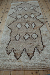 Shaggy vintage Moroccan rug pile with primitive brown motifs, subtle abrashes, and a small stain.