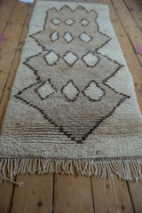 Ivory hand-knotted fringe and textured pile of a vintage Moroccan runner with geometric motifs.
