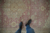 Faded dusty cochineal red and antique ivory ornate floral vinery on a distressed Kayseri carpet.