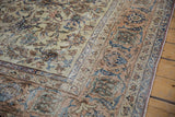 Distressed Isfahan carpet corner showcasing antique ivory, pale apricot, and navy blue floral vine patterns.