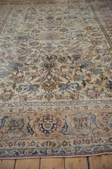 Distressed Isfahan rug's apricot border, indigo floral arabesques, and visible pile wear.