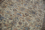 Ivory field of distressed Isfahan rug, showing worn texture and faded floral vinery.