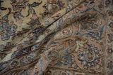 Folded distressed Isfahan rug reveals worn pile, apricot, navy, and ivory floral vinery.
