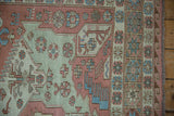 Soumac flat weave with geometric starbursts, blush, blue, green tones, and side selvage.