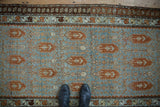 Distressed Malayer runner's faded blue field, rust boteh pattern, main border, and shoes for scale.