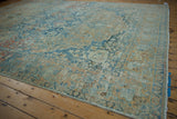 Vintage distressed Persian carpet displaying even wear, soft blue, and dusty gold tones.