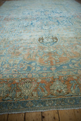 Worn border detail of vintage Persian rug with blue, terracotta floral patterns and fringe.