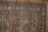 Distressed Karaja rug's geometric pattern in dusty rose and denim blue with visible pile wear.