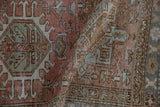 Distressed Karaja rug detail: hook-and-latch geometric patterns in dusty rose and pale blue.