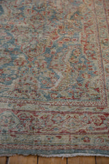 Detail of a distressed Mahal rug, showing worn blue, red floral motifs with exposed foundation.