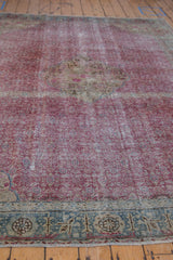 Angled view across the distressed fuchsia Herati field of a vintage Kayseri carpet.