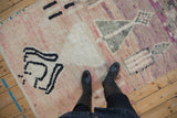 Plush vintage Moroccan rug with abstract black and dusty rose patterns, beneath boots.