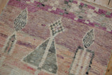 Distressed pile texture of vintage Moroccan rug featuring abstract dusty rose and purple motifs.