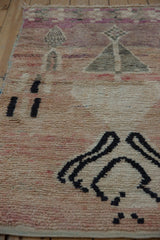 Abstract black and dusty rose motifs on the distressed Moroccan rug's textured pile.