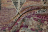 Textured pile of a vintage distressed Moroccan rug with faded rose and ivory tones.
