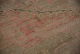 Soft, varied pile texture of a distressed Oushak rug with faded rose and coffee brown geometrics.
