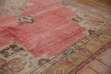 Evenly worn low pile across the abrashed dusty red field of a vintage Oushak rug.