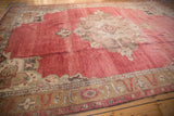Angled view of a distressed Oushak carpet, showing the oversized medallion on a time-softened red ground.