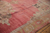 Detail of the abrashed dusty red field and sand-colored spandrel on a distressed Oushak carpet.
