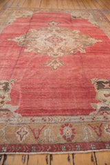 Low angle view across the distressed pile and abrashed cochineal red field of a vintage Oushak rug.