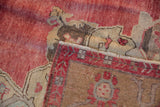Folded corner showing the hand-knotted reverse and worn cochineal red pile of a distressed Oushak rug.