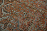 Textured surface of a distressed Mehrivan carpet with geometric vines and pale terracotta tones.