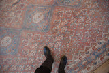 Detail of a distressed Qashqai carpet's pale blue medallion against the faded red lattice field.