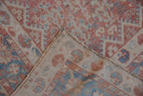 Folded corner of a distressed Qashqai carpet revealing its hand-knotted foundation and side cord.