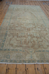 Distressed vintage Malayer rug runner showing geometric-floral design and faded blue, ivory, and brown tones.